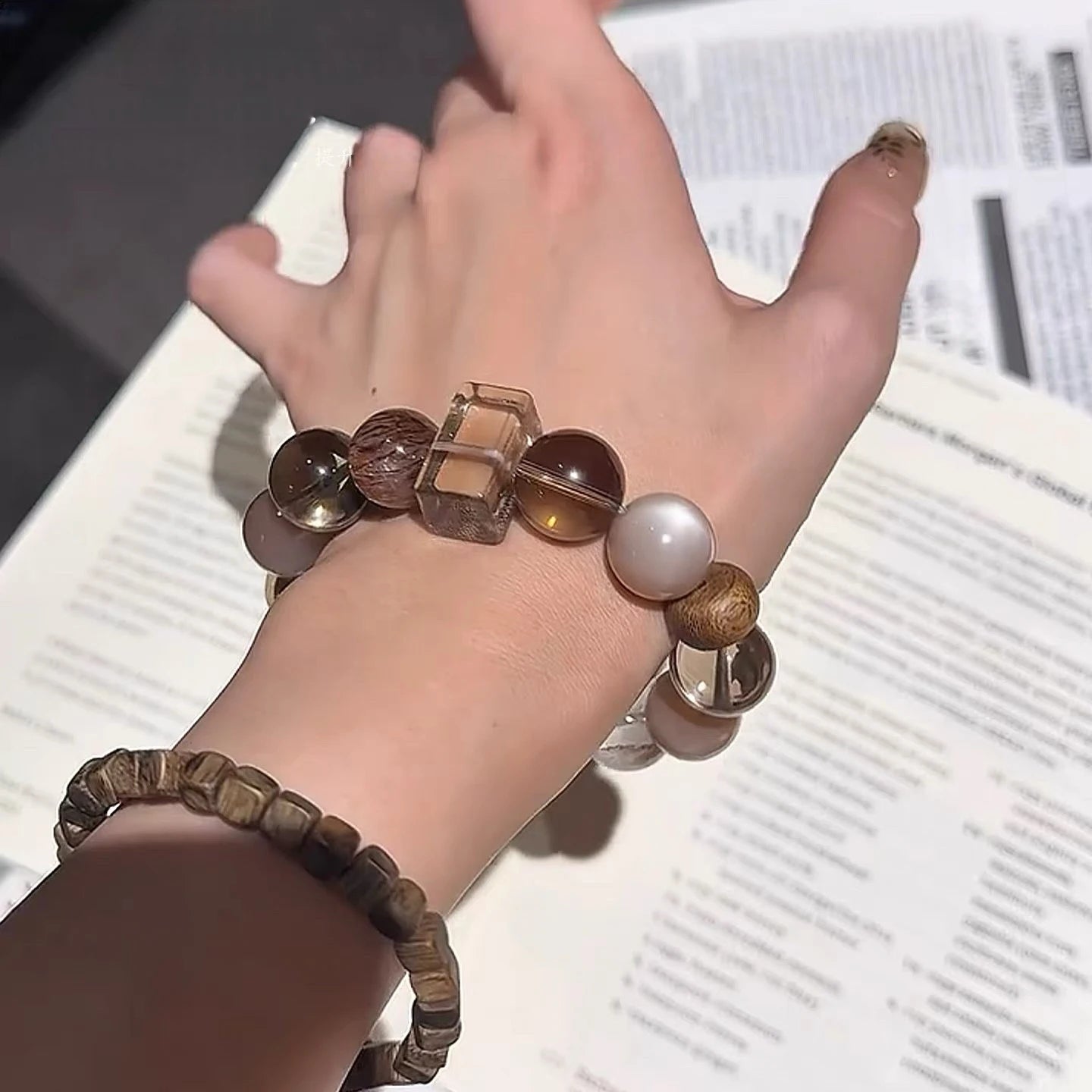 Model showcasing layered black super seven, moonstone, and smoky quartz bracelet for energetic stability and spiritual harmony.