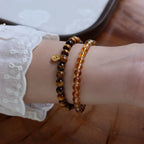 Woman wearing double wrap citrine and tiger eye bracelet with coin charm for wealth attraction, confidence, and empowered energy.