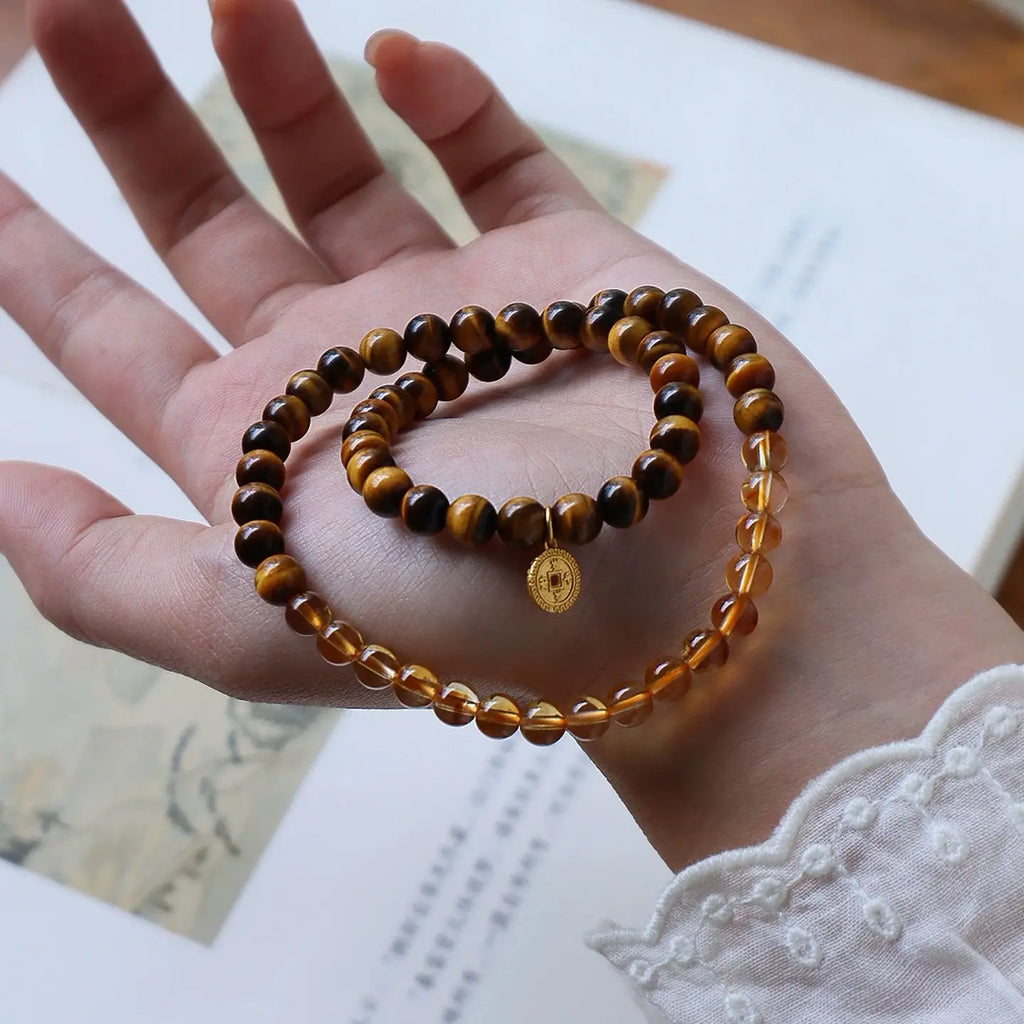 Double wrap citrine and tiger eye bracelet with coin charm displayed as a symbol of abundance, prosperity, and powerful energy.