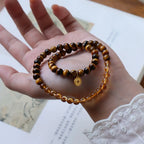 Double wrap citrine and tiger eye bracelet with coin charm displayed as a symbol of abundance, prosperity, and powerful energy.