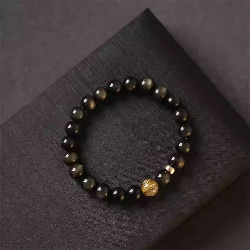 Gold obsidian bracelet featuring a central citrine stone, handcrafted crystal jewelry with glossy black beads.