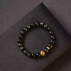 Gold obsidian bracelet featuring a central citrine stone, handcrafted crystal jewelry with glossy black beads.