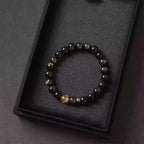 Handmade crystal bracelet highlighting contrast between dark gold obsidian and vibrant citrine center bead.