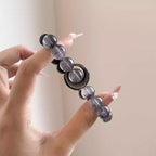 Close-up of a natural crystal bracelet for women with obsidian and grey quartz beads, a handcrafted energy bracelet and gemstone accessory.