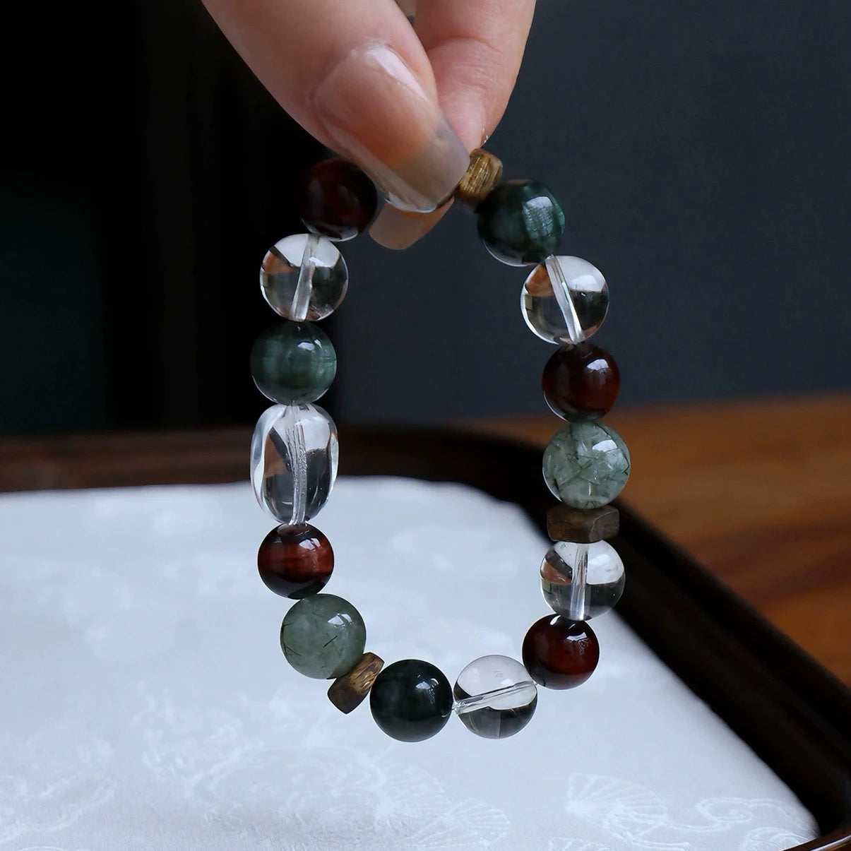 Green aventurine and tiger eye bracelet with clear quartz and natural agarwood beads on a minimalist background.