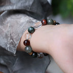 Model wearing a green aventurine and tiger eye bracelet with clear quartz and agarwood beads.