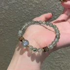 Natural green rutilated quartz, grey moonstone and agarwood bracelet, symbolizing abundance, emotional balance, and spiritual calm.
