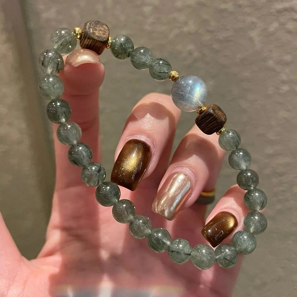 Grey moonstone and agarwood bracelet with green rutilated quartz beads, promoting emotional clarity, stability, and abundance。
