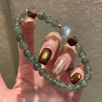 Grey moonstone and agarwood bracelet with green rutilated quartz beads, promoting emotional clarity, stability, and abundance。