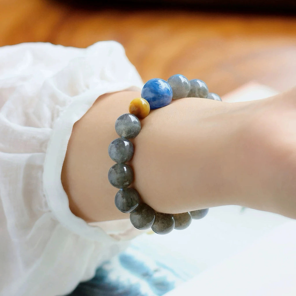 Woman wearing grey moonstone and blue kyanite bracelet for emotional calm, spiritual insight, and balanced energy flow.