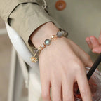 Woman wearing grey moonstone bracelet with gold sun charm, designed for modern balance, intuition, and vital energy – stylish crystal accessory.