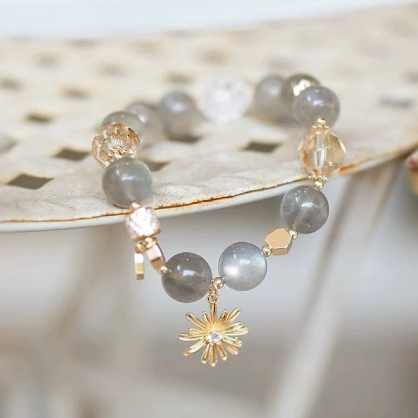 Grey moonstone crystal bracelet featuring a gold sun charm, promoting vitality, emotional clarity, and modern spiritual balance – natural crystal bracelet.