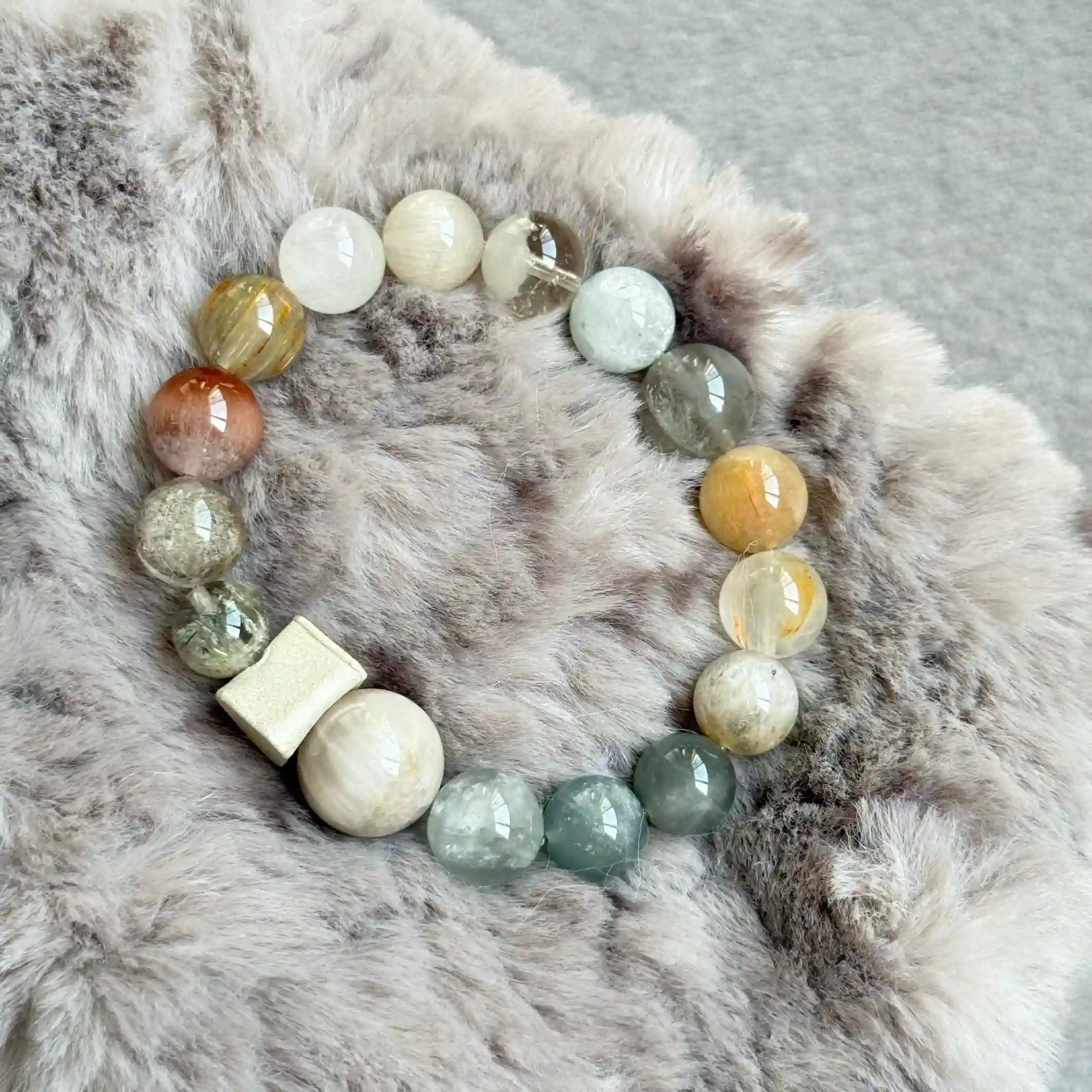 Multicolor rutilated quartz and phantom crystal bracelet showing natural inclusions and layered textures.