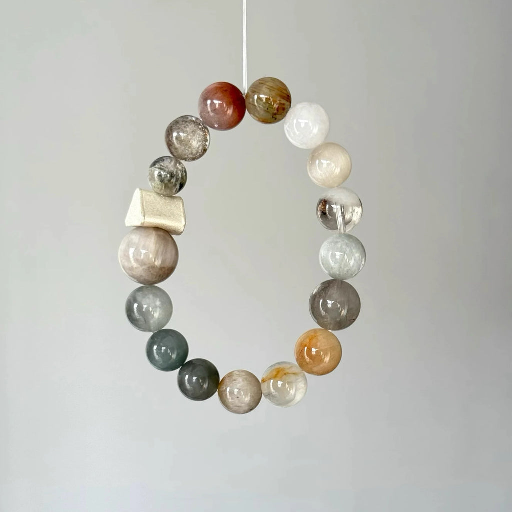 Artisan crystal bracelet combining rutilated quartz and phantom quartz in an organic design.