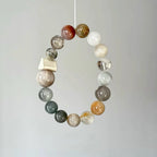 Artisan crystal bracelet combining rutilated quartz and phantom quartz in an organic design.