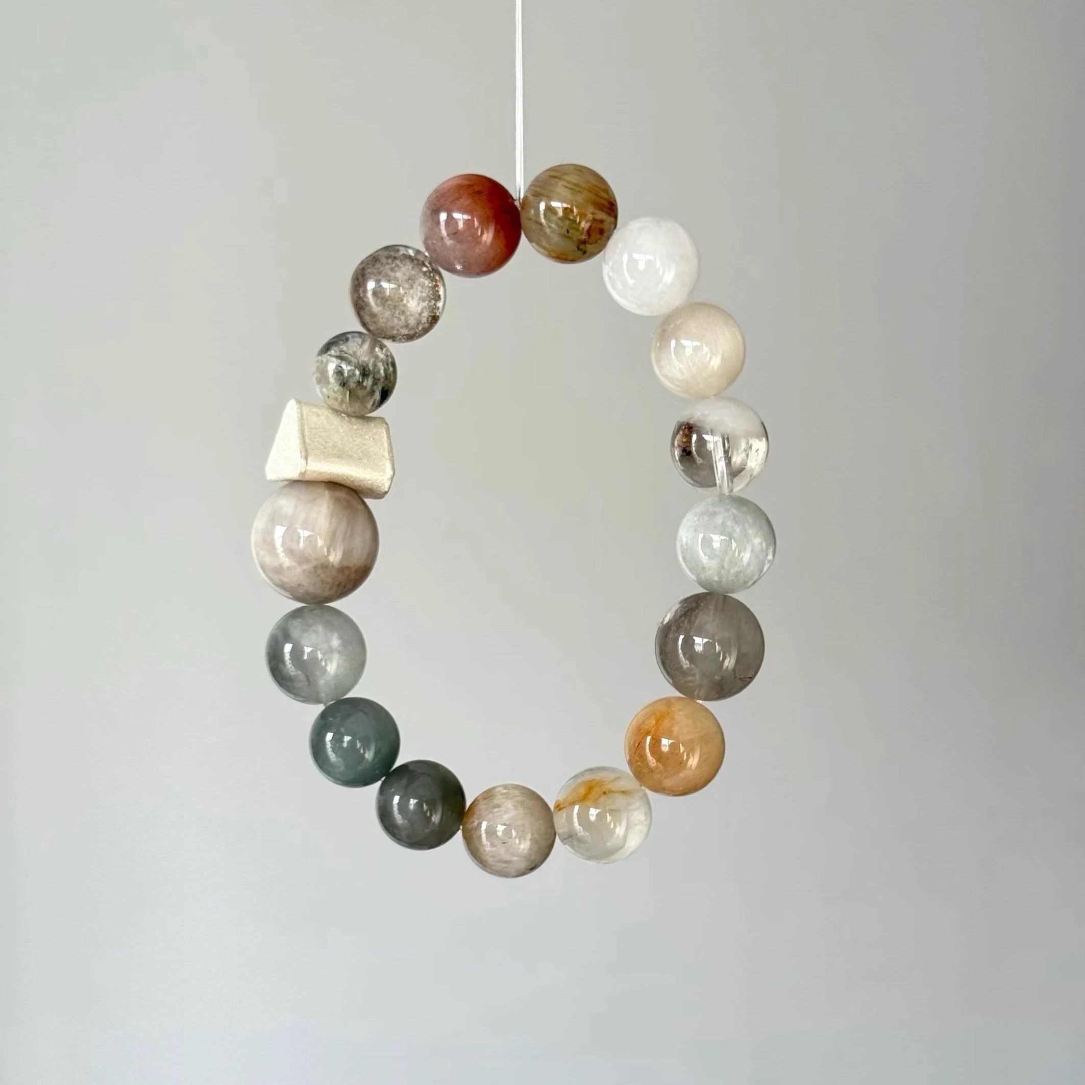 Artisan crystal bracelet combining rutilated quartz and phantom quartz in an organic design.