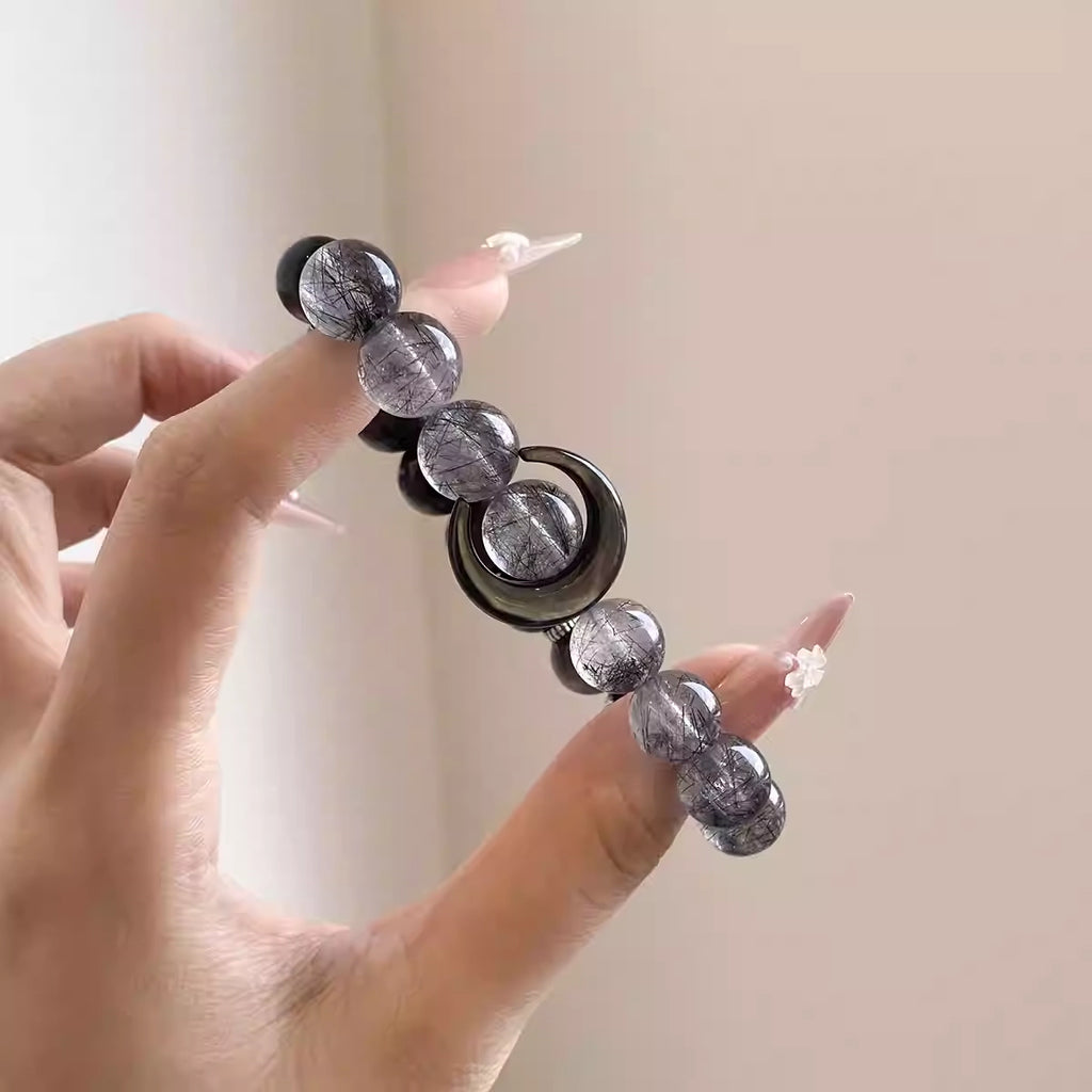 Close-up of a natural crystal bracelet with obsidian and grey quartz beads, a handcrafted energy bracelet and gemstone accessory.