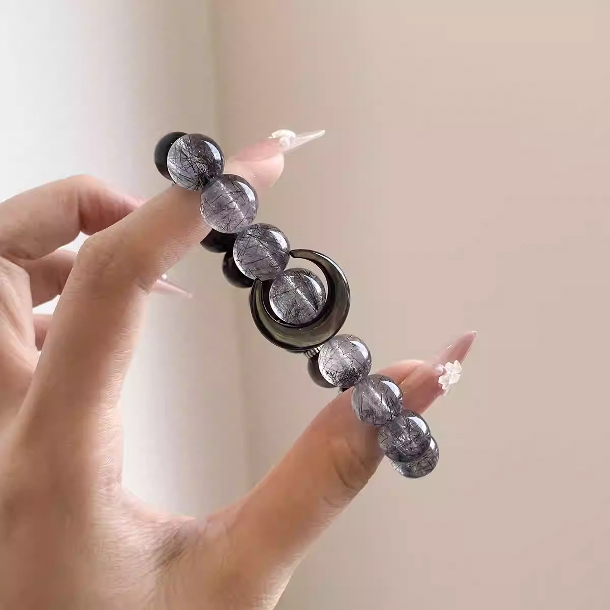 Close-up of a natural crystal bracelet for women with obsidian and grey quartz beads, a handcrafted energy bracelet and gemstone accessory.